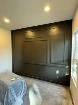Dark painted picture-frame panel accent wall in a bedroom